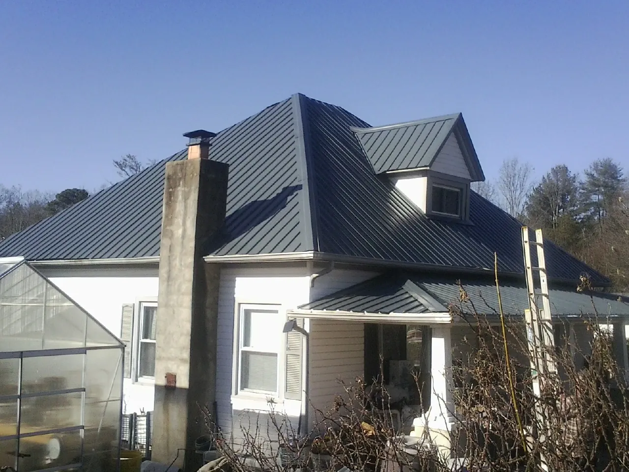 Dark blue standing seam metal roof on a white farmhouse with dormer — Slate & Tile Roof Repair by Roofing Brothers in Mccordsville