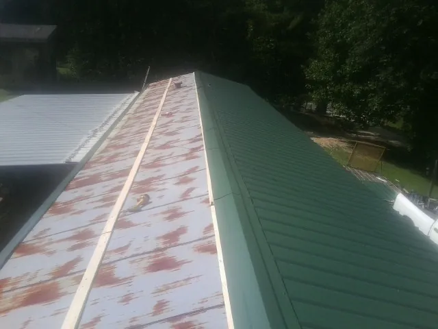 Old rusted panels beside newly installed green metal roofing — Wind Damage Roof Repair by Roofing Brothers in Mccordsville