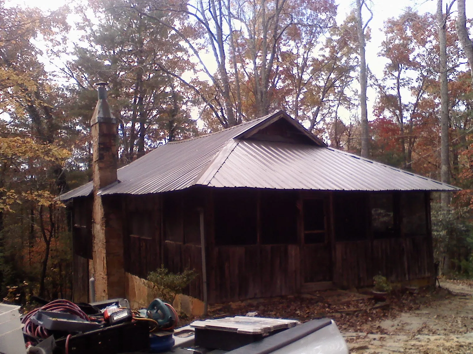 Brown metal hip roof on an old cabin with a stone chimney in Mccordsville