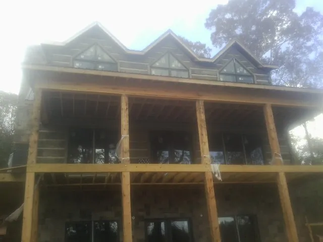 Dormers and porch framing on a large log home under construction — Roof Coating work by our crew in Mccordsville
