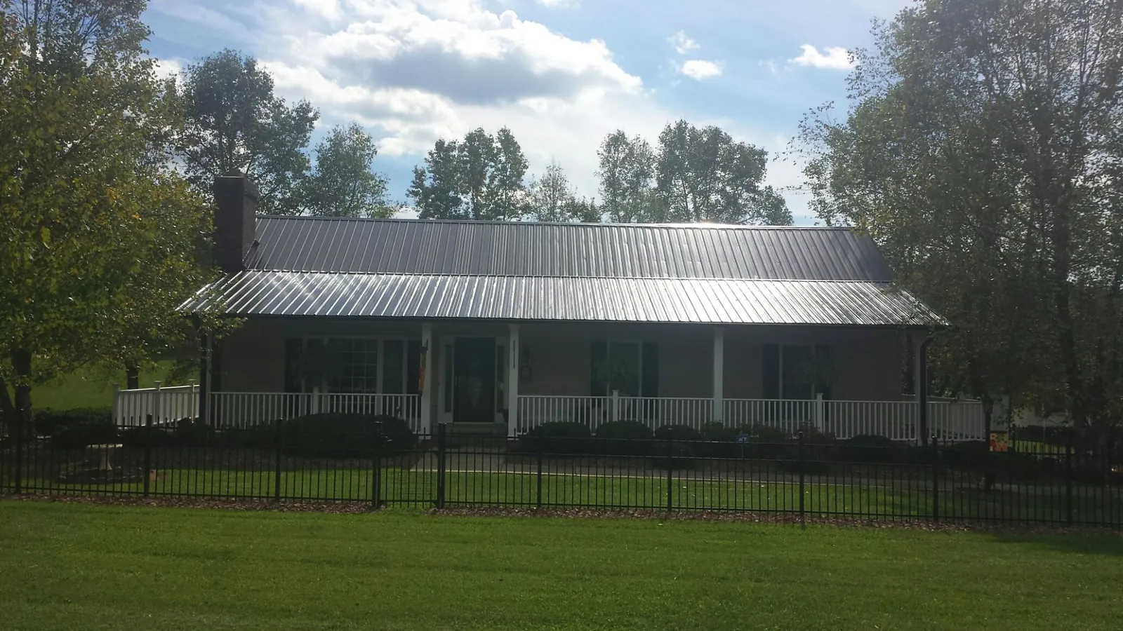 Gray metal roof on a brick ranch with a full width front porch — Gutter Guard Installation work by our crew in Mccordsville