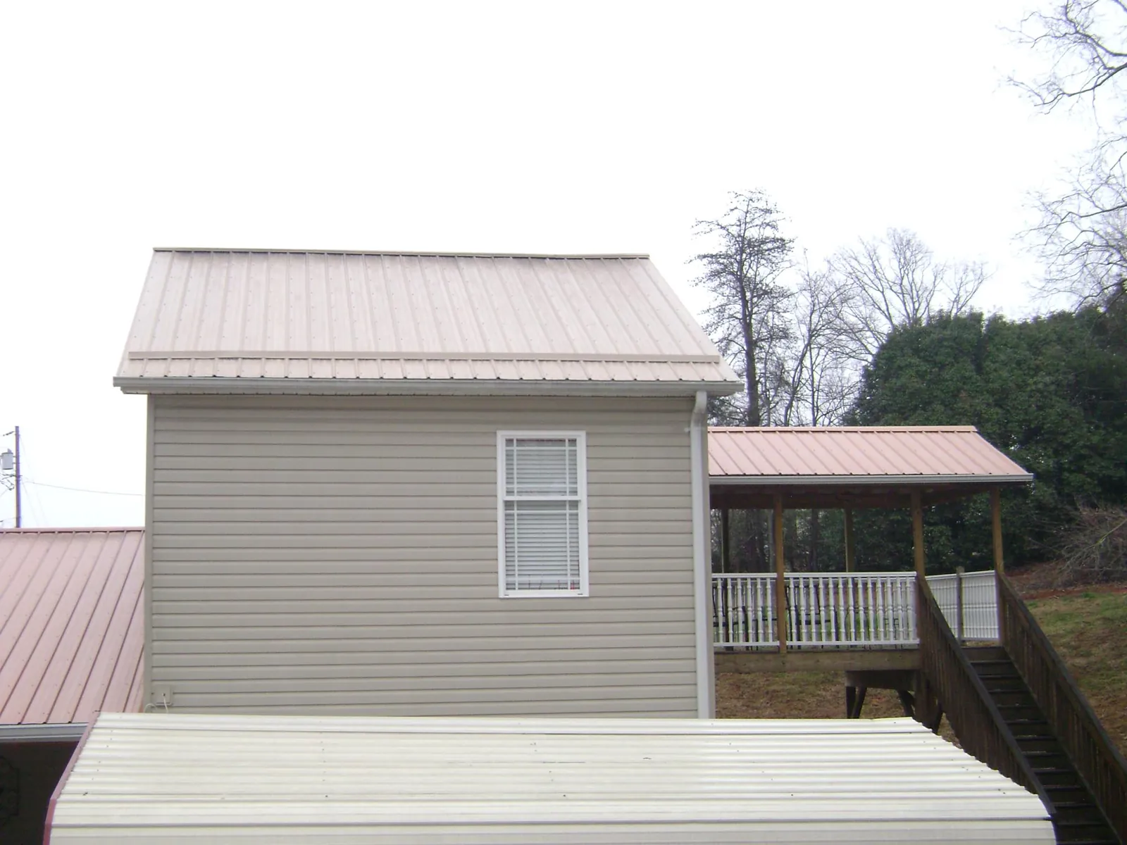 Tan metal roofs on a two story addition and attached porch, from a Roof Replacement job in Mccordsville