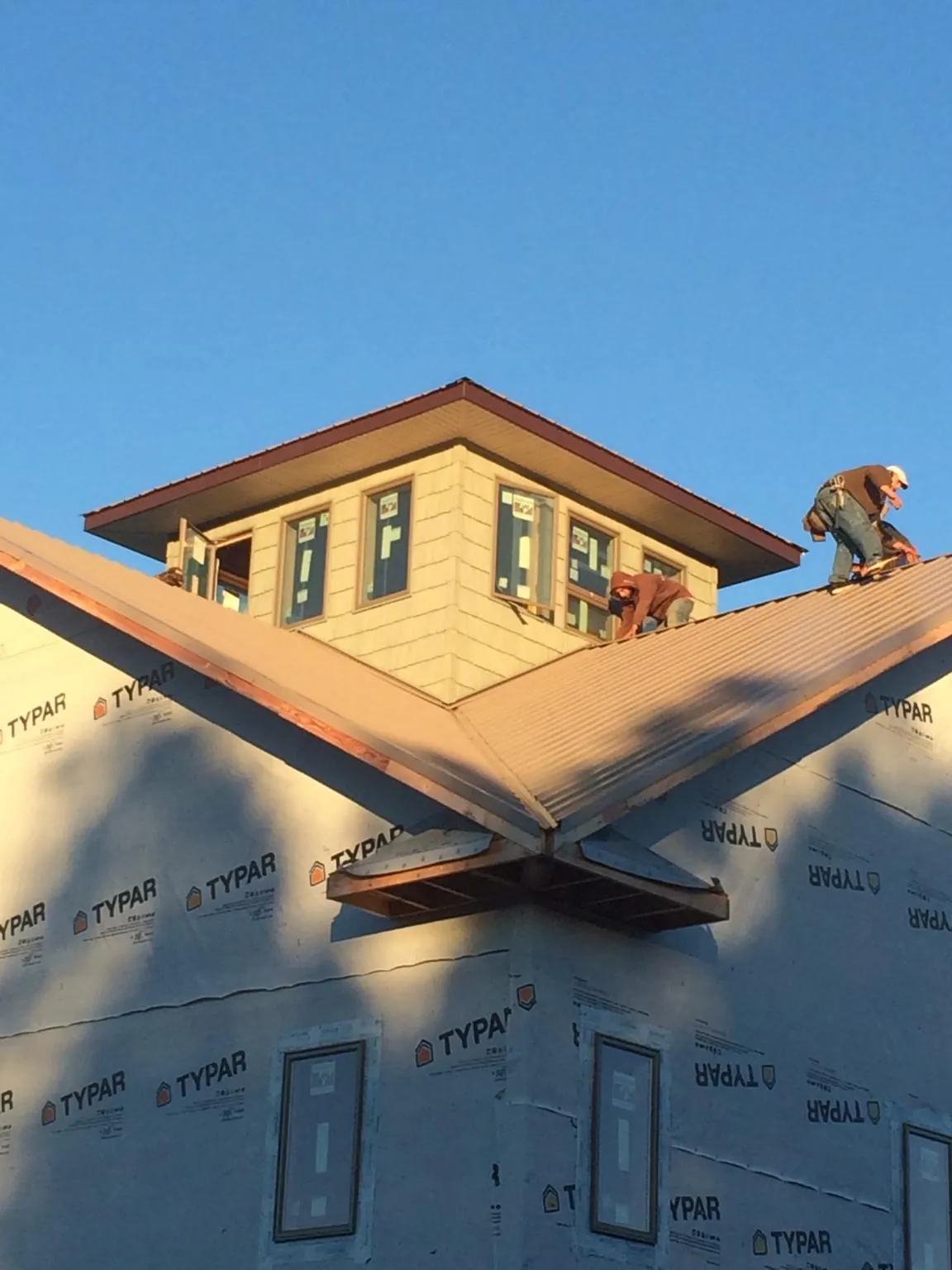 Roofers working around a rooftop cupola on a new metal roof at sunset — Roof Waterproofing in Mccordsville by Roofing Brothers